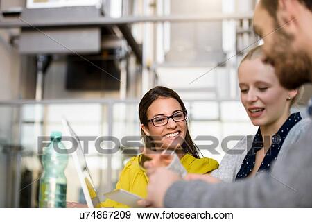 Stock Photo - Male and female designers pointing at laptop on design studio desk. Fotosearch