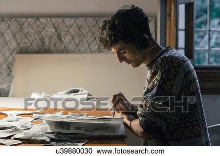 Stock Image - Male artist drawing in sketchbook in artists studio. Fotosearch