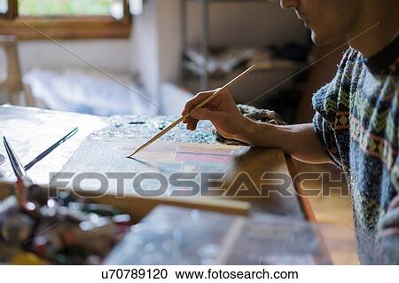 Stock Image - Male artist painting canvas in artists studio, cropped. Fotosearch