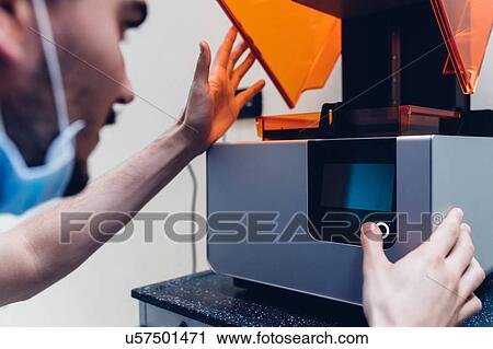 Stock Image - Male dentist using 3D printer. Fotosearch