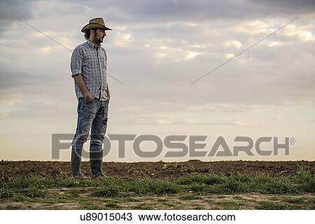 Stock Image - Male farmer standing on farmland.. Fotosearch