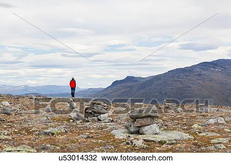 Stock Image - Male hiker looking out at mountain landscape, rear view, Jotunheimen National Park, Lom, Oppland, Norway. Fotosearch
