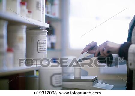 Stock Photo - Male pharmacist weighing medical drug on pharmacy scales, cropped. Fotosearch