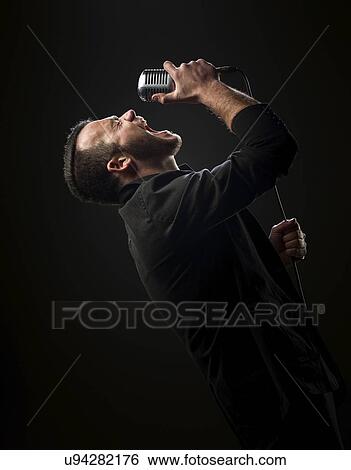 Stock Photograph - Male singer on stage with microphone.. Fotosearch