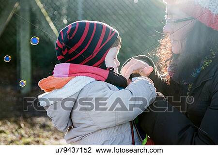 Male toddler and mother blowing bubbles in park View Large Photo Image Stock Image - Male toddler and mother blowing bubbles in park. Fotosearch