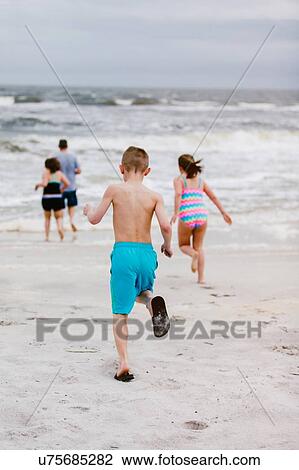 Man and children running toward sea from beach, rear view, Dauphin Island, Alabama, USA View Large Photo Image Stock Image - Man and children running toward sea from beach, rear view, Dauphin Island, Alabama, USA. Fotosearch