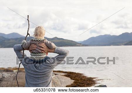 Stock Photo - Man and son looking out at fjord, Aure, More og Romsdal, Norway. Fotosearch