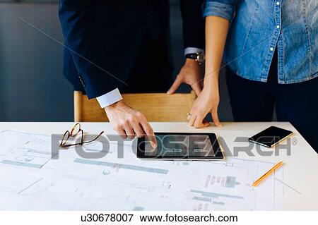 Man and woman in meeting, looking at digital tablet, mid section View Large Photo Image Stock Photo - Man and woman in meeting, looking at digital tablet, mid section. Fotosearch