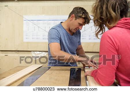 Stock Image - Man and woman in workshop, making ski equipment. Fotosearch