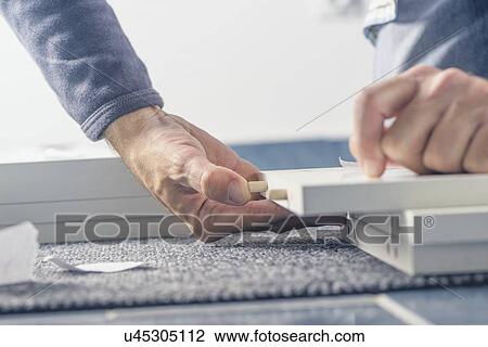 Stock Image - Man assembling furniture at home, hand with dowel pins.. Fotosearch