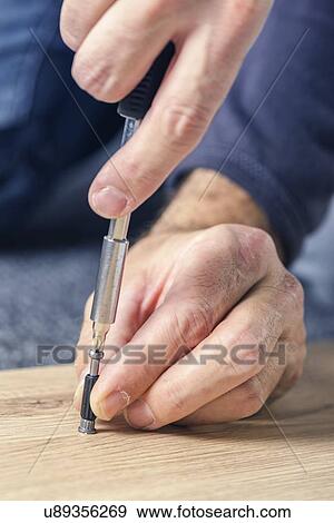 Stock Photo - Man assembling furniture at home, hand with screwdriver.. Fotosearch