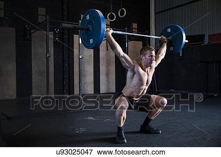 Man exercising in gym, using barbell, front squat position View Large Photo Image Stock Photo - Man exercising in gym, using barbell, front squat position. Fotosearch