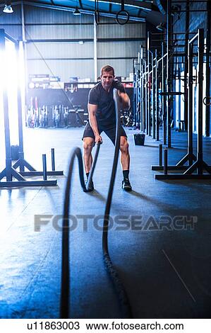 Man exercising in gym, using battle ropes View Large Photo Image Stock Image - Man exercising in gym, using battle ropes. Fotosearch