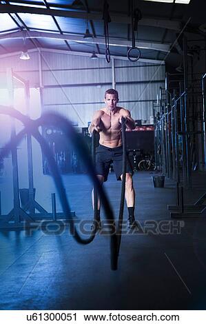 Man exercising in gym, using battle ropes View Large Photo Image Stock Image - Man exercising in gym, using battle ropes. Fotosearch