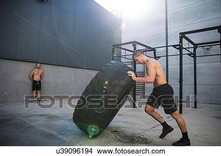 Man exercising in gymnasium, lifting tire View Large Photo Image Picture - Man exercising in gymnasium, lifting tire. Fotosearch