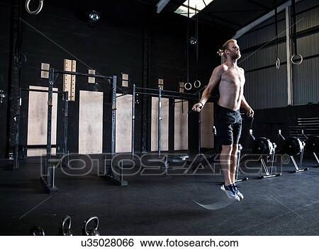 Man exercising in gymnasium, skipping with speed rope View Large Photo Image Stock Photograph - Man exercising in gymnasium, skipping with speed rope. Fotosearch