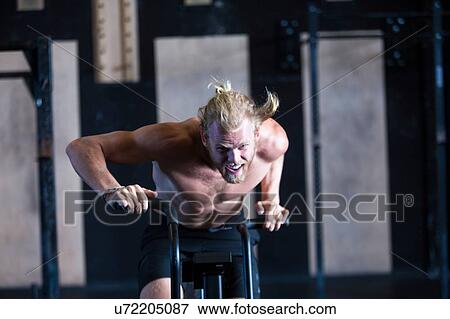 Man exercising in gymnasium, using air resistance exercise bike View Large Photo Image Stock Photo - Man exercising in gymnasium, using air resistance exercise bike. Fotosearch