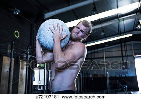 Man exercising in gymnasium, using atlas stone View Large Photo Image Stock Image - Man exercising in gymnasium, using atlas stone. Fotosearch