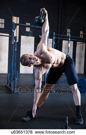 Stock Photo - Man exercising in gymnasium, using kettlebell. Fotosearch