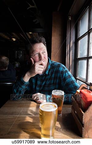 Stock Photo - Man having beer looking out of window. Fotosearch