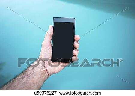 Stock Photo - Man holding mobile phone by swimming pool.. Fotosearch