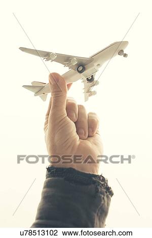 Stock Image - Man holding toy airplane.. Fotosearch