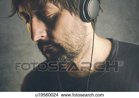 Man listening to music on headphones with eyes closed. View Large Photo Image Picture - Man listening to music on headphones with eyes closed.. Fotosearch