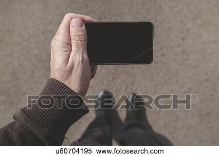 Stock Photography - Man looking at smartphone screen on street.. Fotosearch