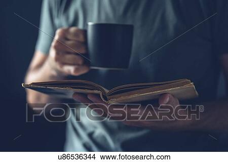 Picture - Man reading book and drinking coffee.. Fotosearch