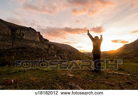 Man standing in rural setting, arms raised towards sun View Large Photo Image Stock Image - Man standing in rural setting, arms raised towards sun. Fotosearch