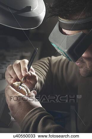 Stock Image - Man working on dental prosthesis.. Fotosearch