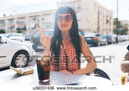 Mature female hipster smoking cigarette at sidewalk cafe View Large Photo Image Stock Photograph - Mature female hipster smoking cigarette at sidewalk cafe. Fotosearch