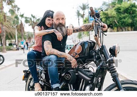 Stock Photo - Mature hipster couple astride motorcycle, Valencia, Spain. Fotosearch