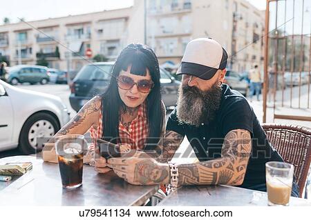Mature hipster couple looking at smartphone at sidewalk cafe, Valencia, Spain View Large Photo Image Picture - Mature hipster couple looking at smartphone at sidewalk cafe, Valencia, Spain. Fotosearch