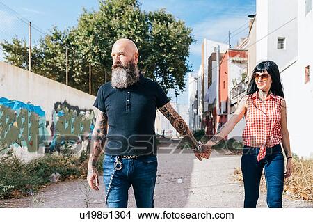 Picture - Mature hipster couple strolling down alleyway. Fotosearch