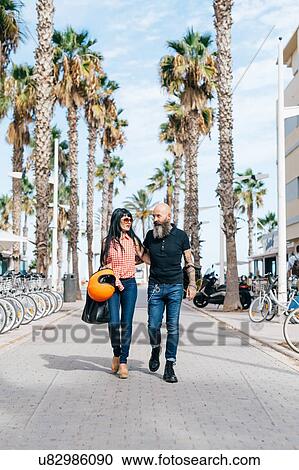 Stock Image - Mature hipster couple strolling on pedestrian area, Valencia, Spain. Fotosearch