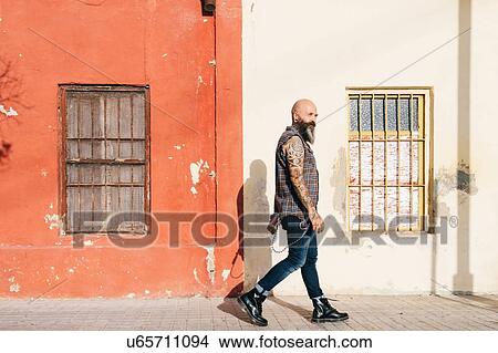Mature male hipster walking along sidewalk View Large Photo Image Picture - Mature male hipster walking along sidewalk. Fotosearch