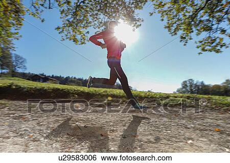Mature male runner running down sunlit rural dirt track View Large Photo Image Stock Photograph - Mature male runner running down sunlit rural dirt track. Fotosearch