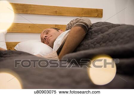 Stock Photography - Mature man lying on his side asleep in bed. Fotosearch