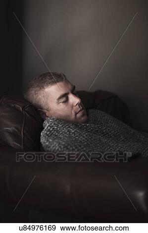Stock Photo - Mature man wrapped in blanket asleep on armchair. Fotosearch