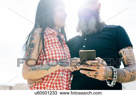 Mature tattooed hipster couple looking at smartphone View Large Photo Image Stock Image - Mature tattooed hipster couple looking at smartphone. Fotosearch