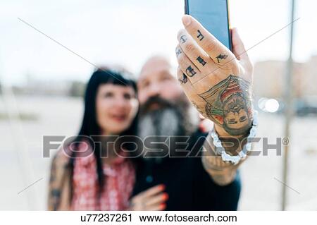 Mature tattooed hipster couple taking selfie, close up of hand View Large Photo Image Stock Image - Mature tattooed hipster couple taking selfie, close up of hand. Fotosearch