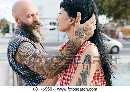 Stock Photo - Mature tattooed hipster man with hand in girlfriend's hair. Fotosearch