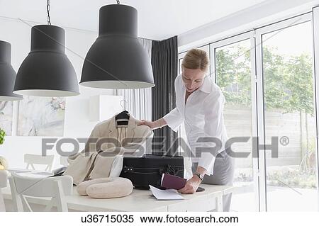 Stock Photography - Mature woman packing suitcase and passport. Fotosearch