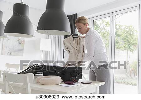 Mature woman packing suitcase at table View Large Photo Image Stock Photo - Mature woman packing suitcase at table. Fotosearch