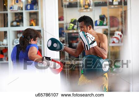 Mature woman practicing boxing with male trainer in gym View Large Photo Image Stock Photo - Mature woman practicing boxing with male trainer in gym. Fotosearch