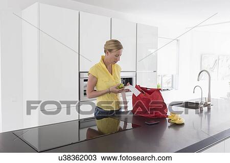 Mature woman unpacking groceries in modern kitchen View Large Photo Image Stock Image - Mature woman unpacking groceries in modern kitchen. Fotosearch