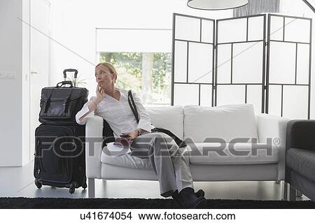 Picture - Mature woman waiting with luggage in modern living room. Fotosearch
