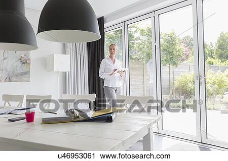 Mature woman working with mobile devices in modern living room View Large Photo Image Stock Image - Mature woman working with mobile devices in modern living room. Fotosearch