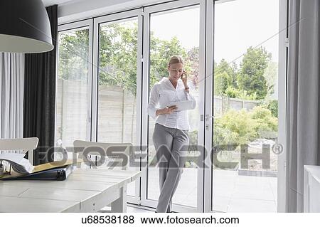 Mature woman working with mobile devices in modern living room View Large Photo Image Stock Photo - Mature woman working with mobile devices in modern living room. Fotosearch